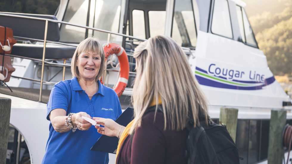 A passenger is greeted by a smiling Cougar Line staff member while boarding in Picton in the Marlborough Sounds, New Zealand.