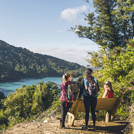 Three woman walkers look out over Ship Cove/Meretoto on the Queen Charlotte Track.