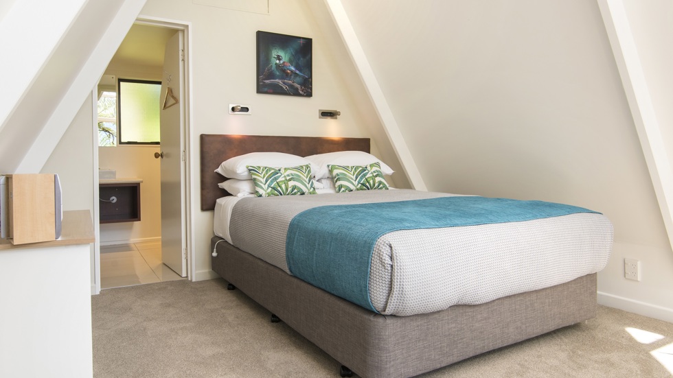 The interior of an A-frame Koru Chalet at Punga Cove, with a queen sized bed and ensuite, in the Marlborough Sounds, New Zealand