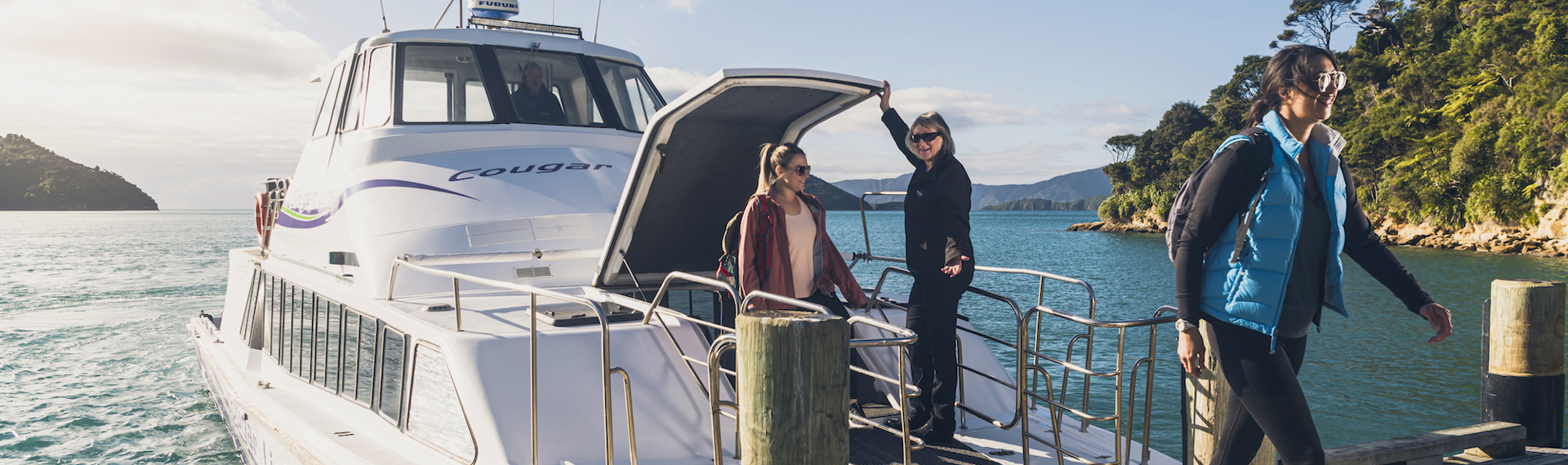 Two walkers disembarking from the Cougar Line boat at Ship Cove/Meretoto ready to walk on the Queen Charlotte Track.