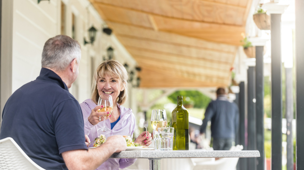 Couple eating dinner outdoors on the balcony at Furneaux Lodge restaurant - on the Queen Charlotte Track.