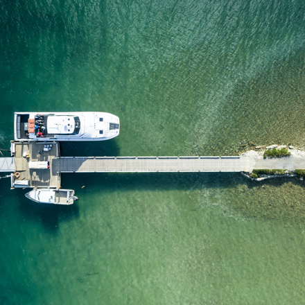 An aerial view of the Furneaux Lodge jetty, boat shed, Cougar Line boat and smaller boats in the Marlborough Sounds, New Zealand.